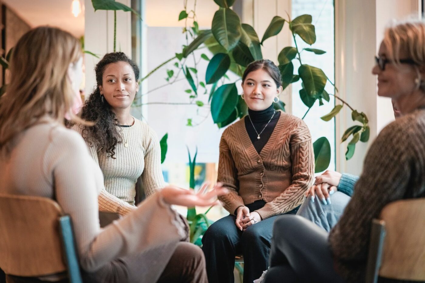 Four women seated in a circle in conversation during a group therapy session