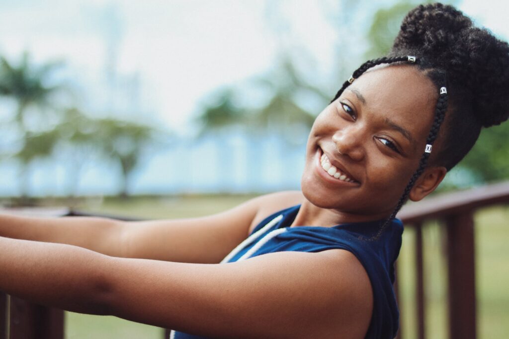 A smiling young woman leaning on a wooden railing outdoors